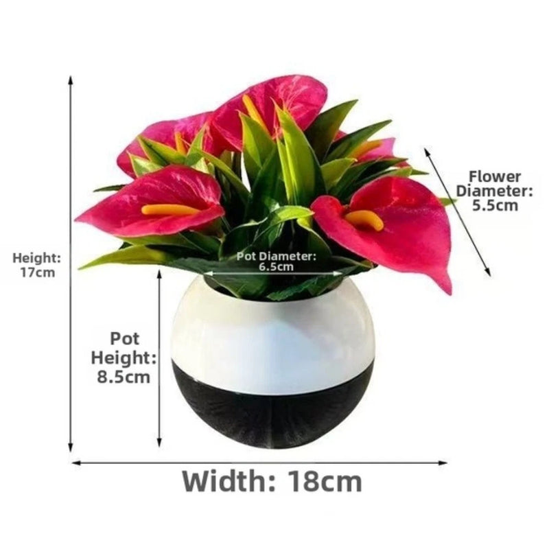 Artificial calla lily plant with magenta flowers and green leaves in white-and-black pot