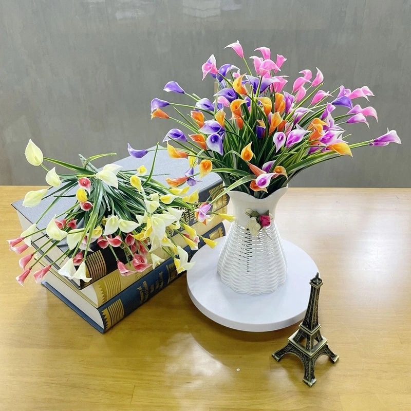 Artificial calla lily flower arrangement with colorful blooms in a white ribbed vase