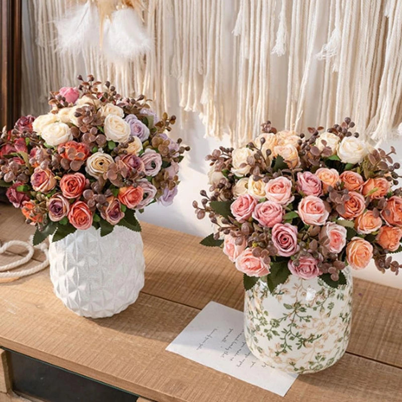Artificial rose flower bouquets in white vases, pink and peach roses with greenery