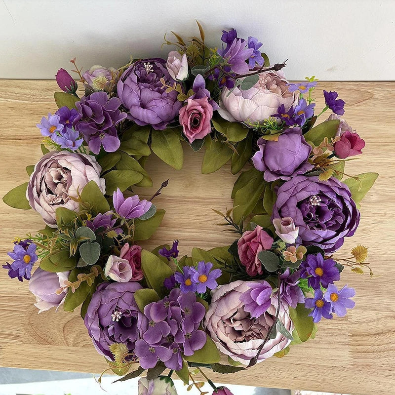 Artificial flower wreath with purple and pink peonies, violet blossoms, and green leaves