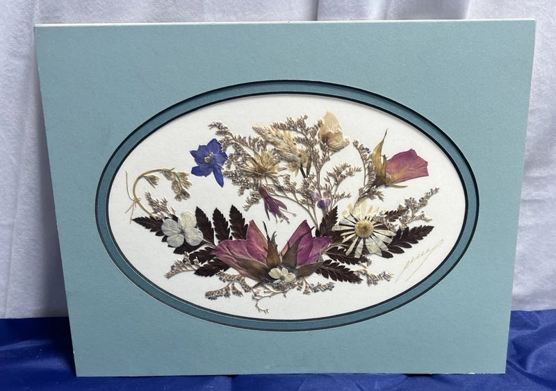 Pressed flower bouquet art print with oval dark frame, botanical dried blooms illustration.