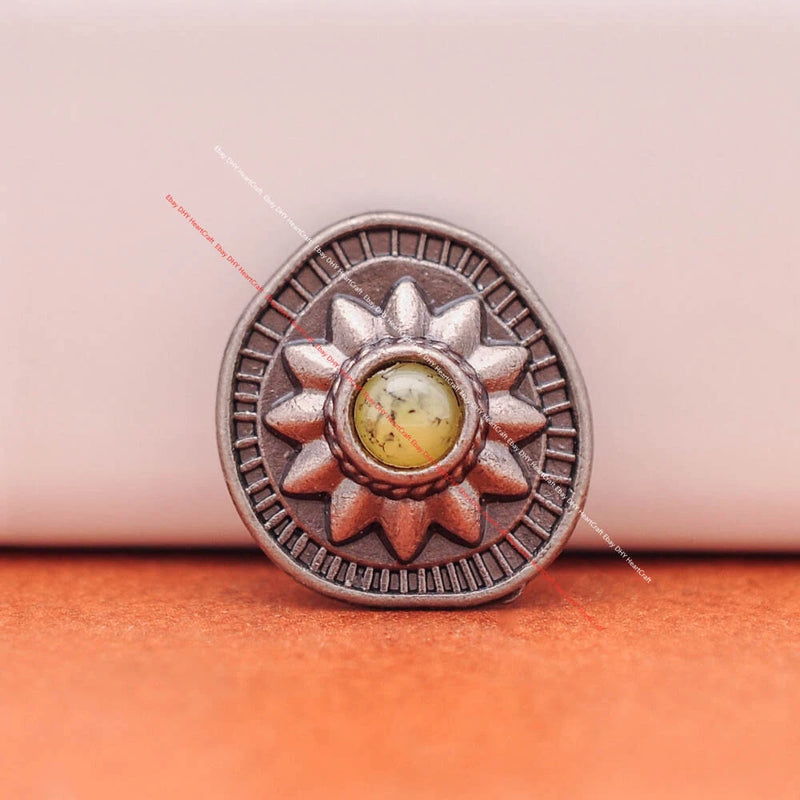 Silver-tone sunflower concho with ornate border and turquoise-like center