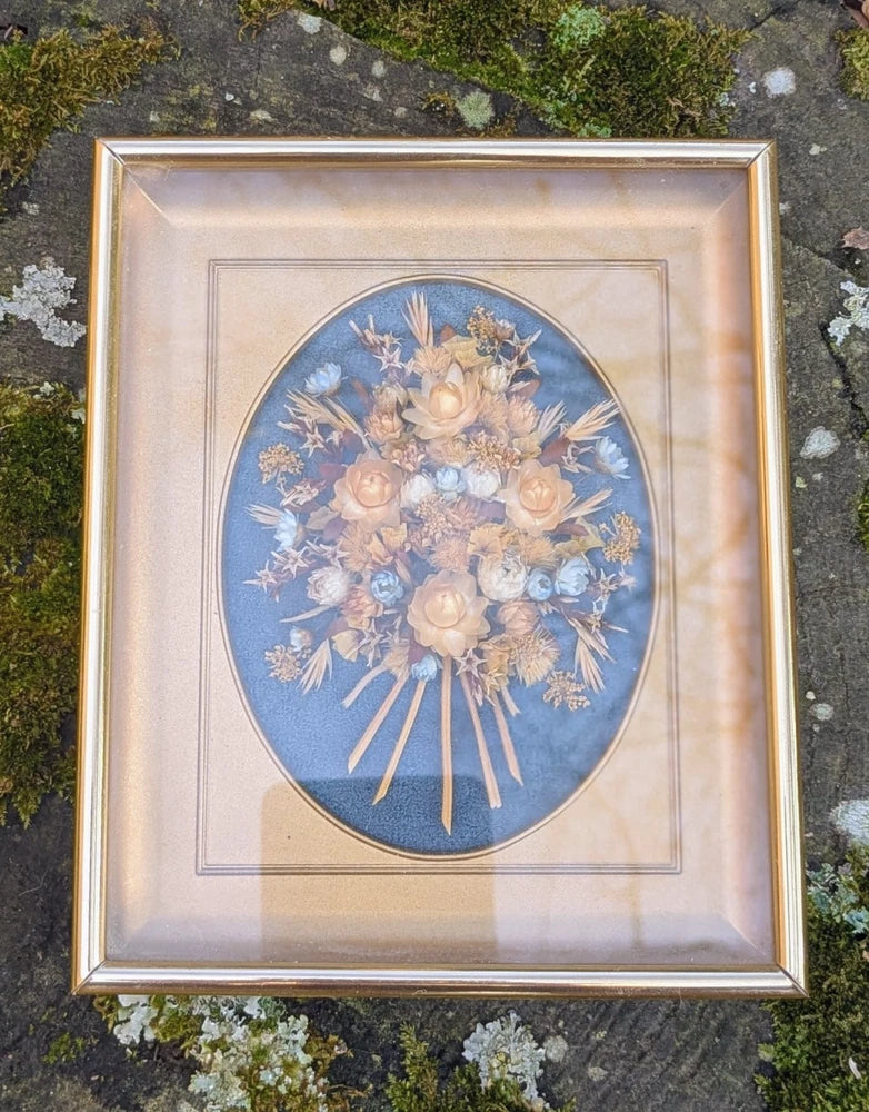 Framed dried flower bouquet wall art with blue oval backing and gold frame