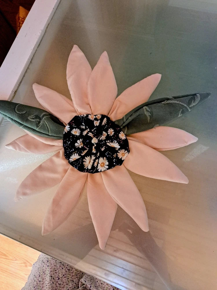 Fabric flower decoration with pink petals and black floral center, tied with dark ribbon