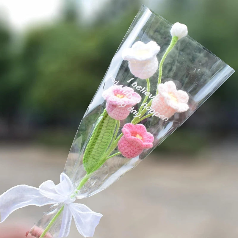 Handmade knitted lily-of-the-valley bouquet with white/pink blooms, green leaves, clear wrap