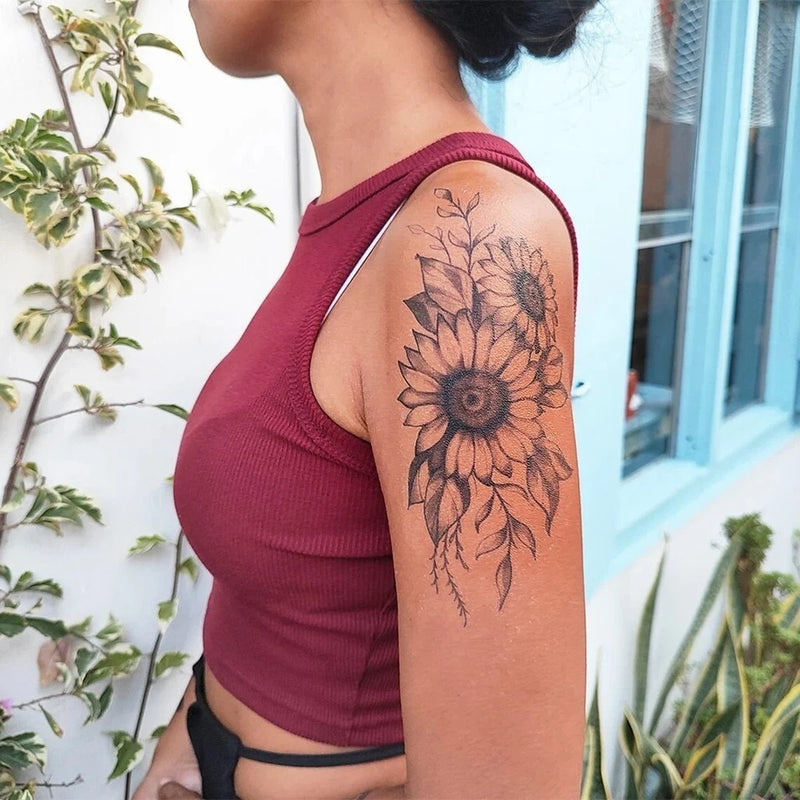 Floral sunflower temporary tattoo on upper arm, black ink outline with leafy details