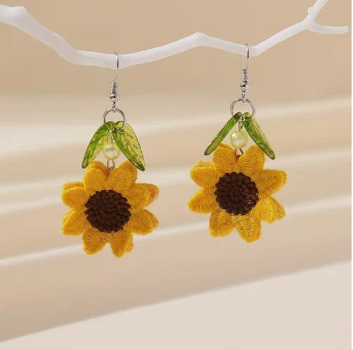Reversible sunflower dangle earrings with yellow fabric flower, dark center, green leaf charms