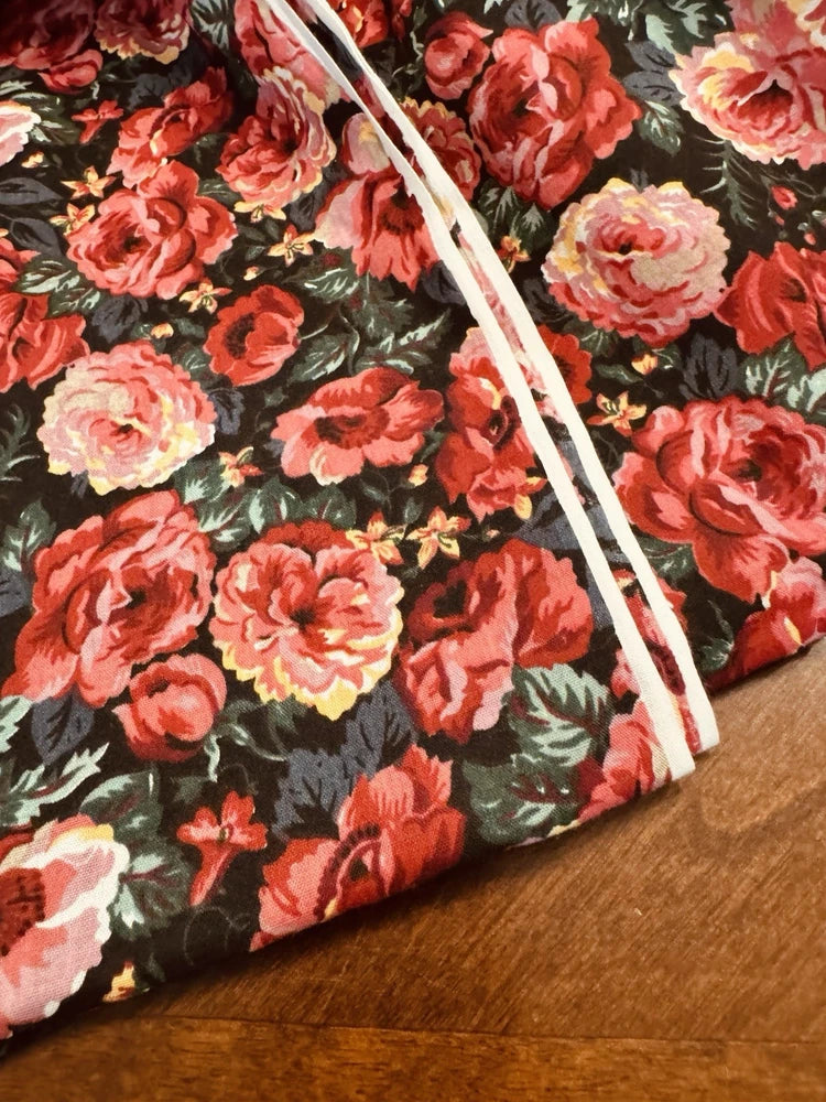 Cotton quilt with vintage rose floral print, red and pink blooms, trimmed edge.