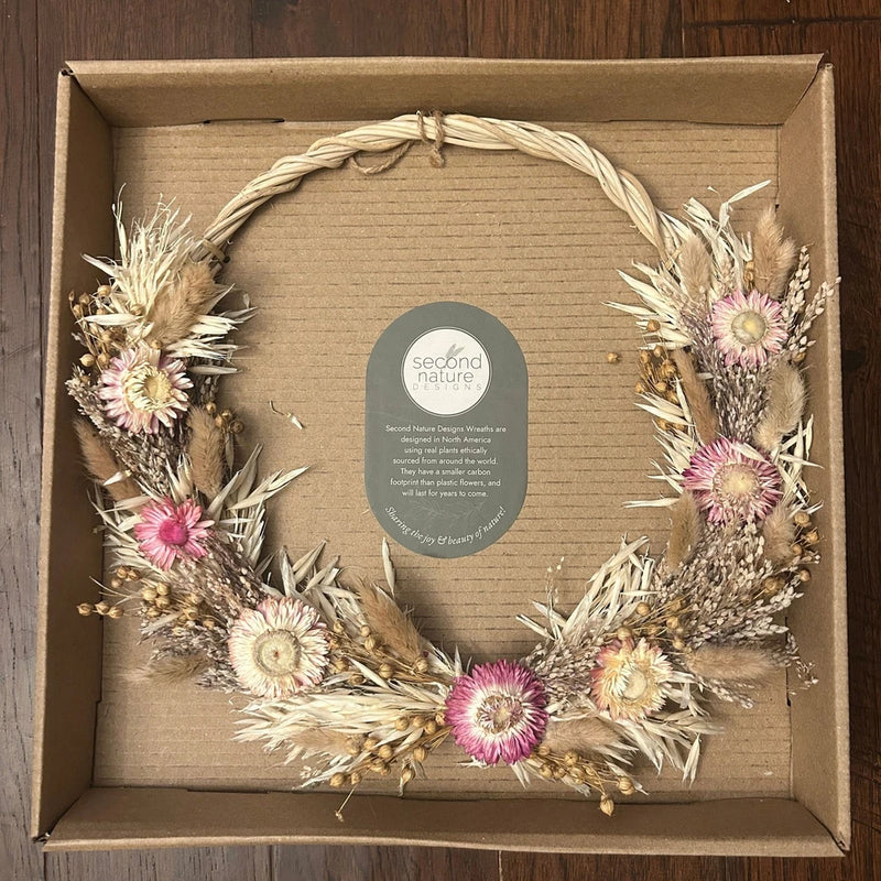 Dried flower wreath with pink and cream blossoms and dried grasses in a ring