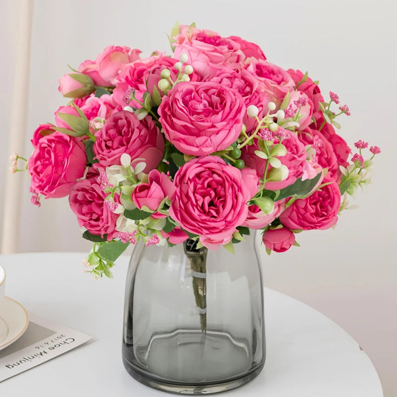 Hot pink silk faux peony flower bouquet with green leaves in clear glass vase