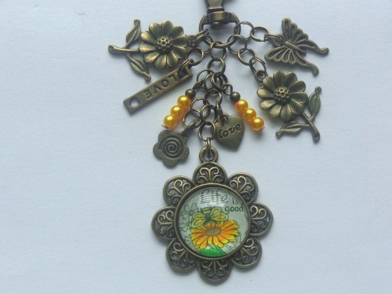 Sunflower-themed metal keychain charm with circular pendant, flower accents, beads, clip ring