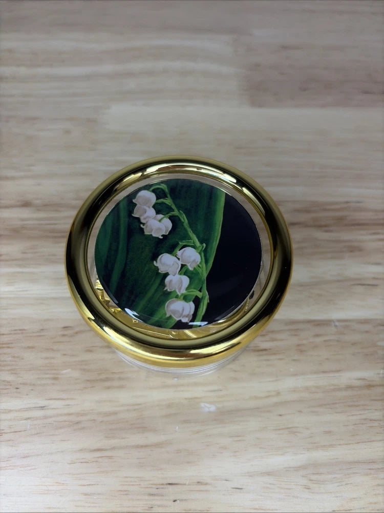 Gold-trimmed round music box with lily of the valley flower insert