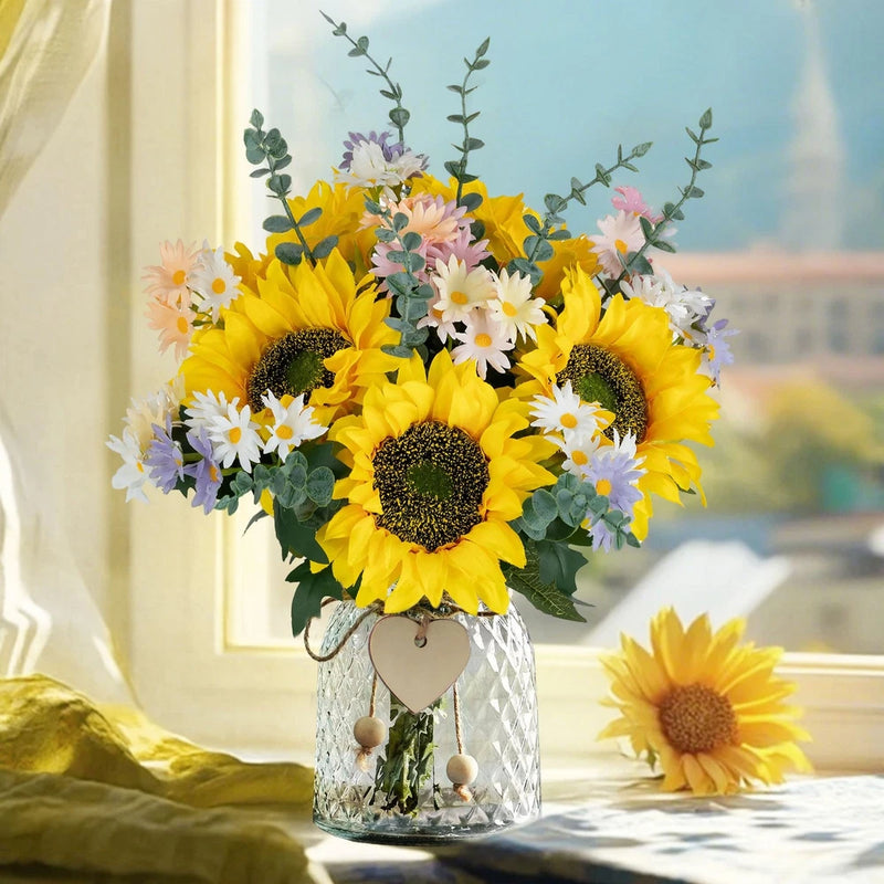 Artificial sunflower and daisy bouquet in clear glass vase with heart charm and beads