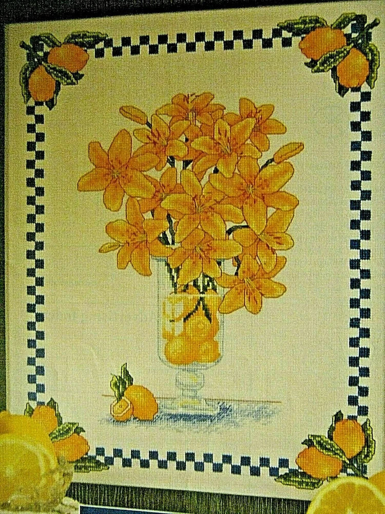 Cross-stitch pattern featuring lemons in a vase with orange flowers and fruit accents