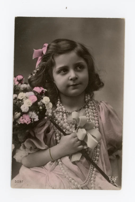 Vintage tinted postcard of a girl in pink dress with pearls, holding flowers