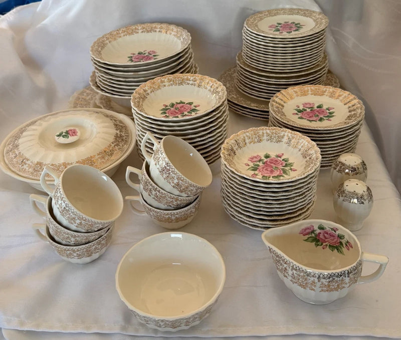 Gold-trimmed floral bouquet dinnerware set: stacked plates, bowls, and teacups