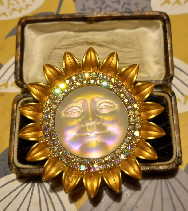 Gold-tone sunburst brooch pin with iridescent moon-face crystal and rhinestone rim
