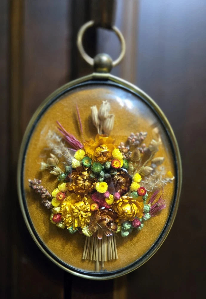 Oval dried-flower bouquet in glass frame with hanging loop