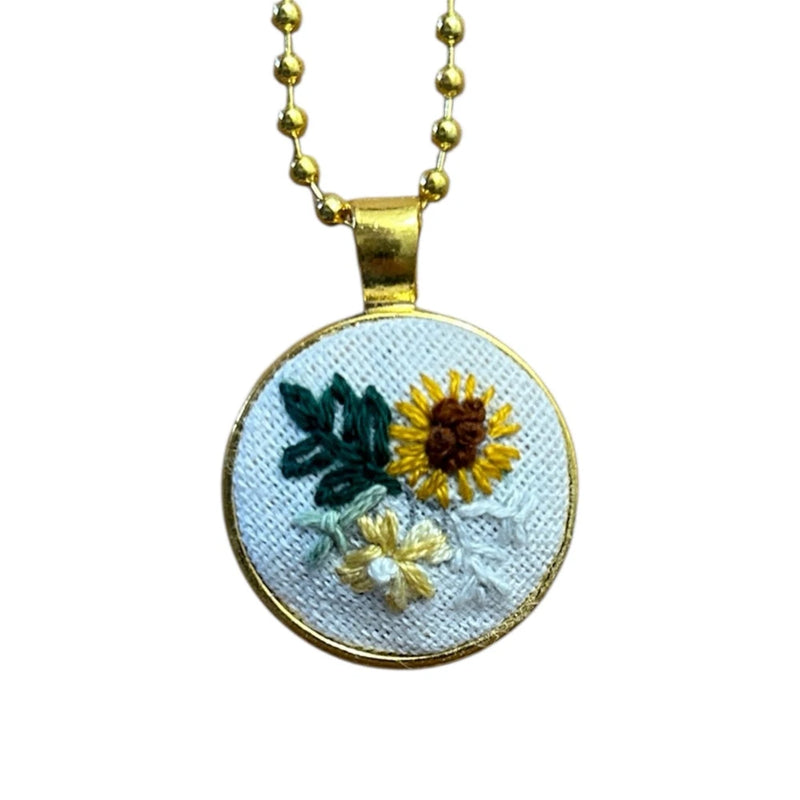 Gold bezeled sunflower pendant necklace with yellow and blue embroidered flowers