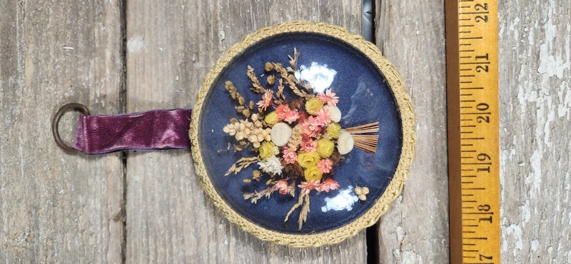 Round vintage domed glass frame with blue backing, dried flowers, and fabric hanging strap