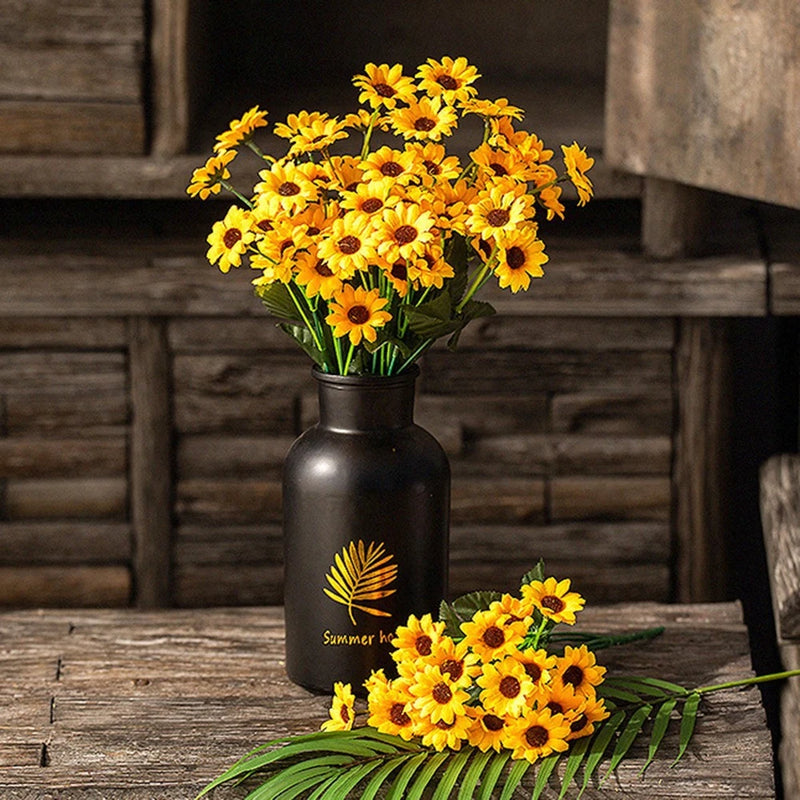 Artificial sunflower bouquet in dark metal vase, with green leaves