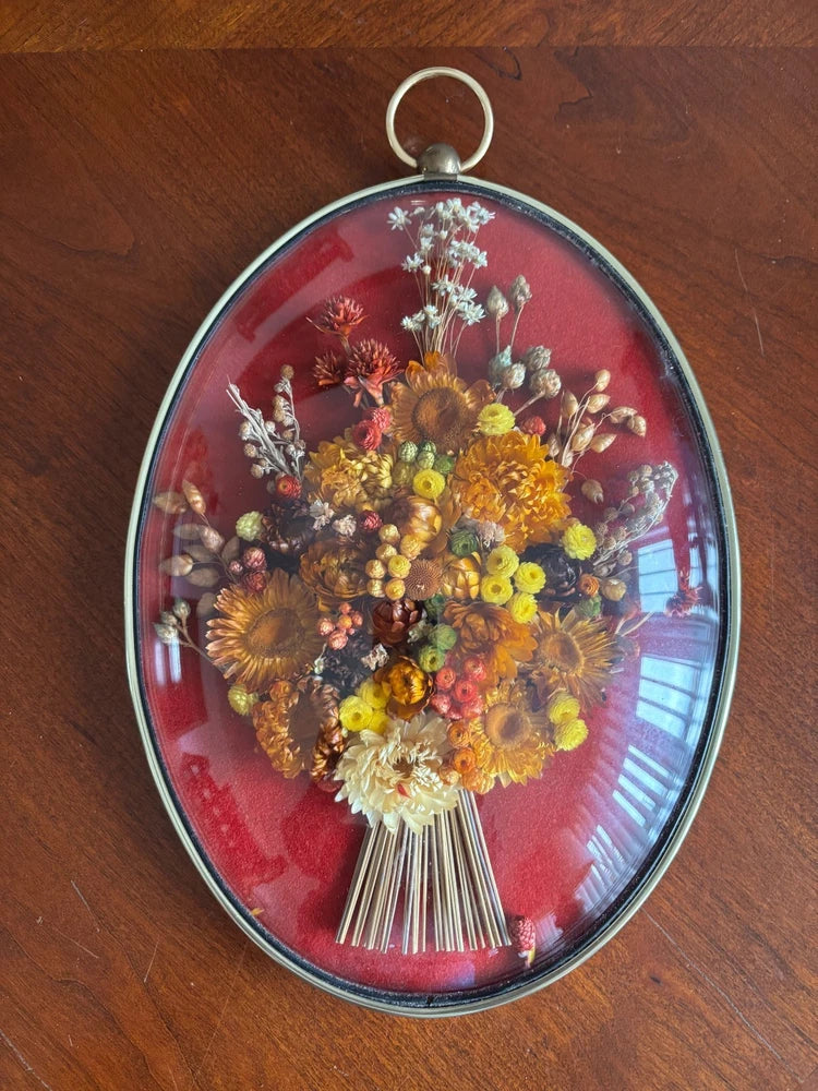 Oval dome glass wall art with dried flower bouquet in a gray metal frame