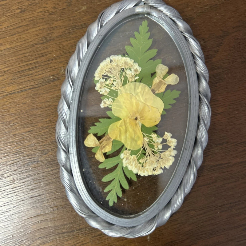 Oval glass framed pressed dried flowers in silver frame with yellow and green blooms