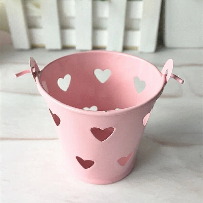 Pink metal planter bucket with heart cutout design and side handles