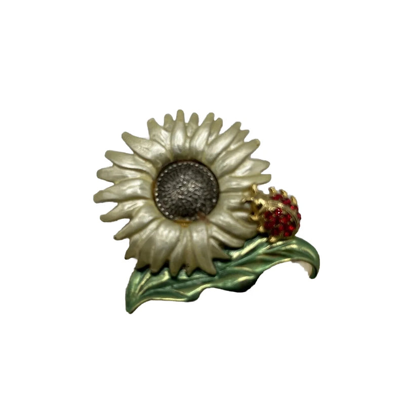 Enamel sunflower brooch with ladybug charm, textured dark center and green leaves.