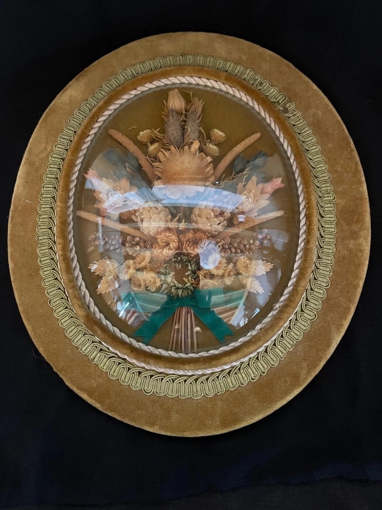 Oval glass dried flower wall art with velvet-brown mat and beaded ribbon trim