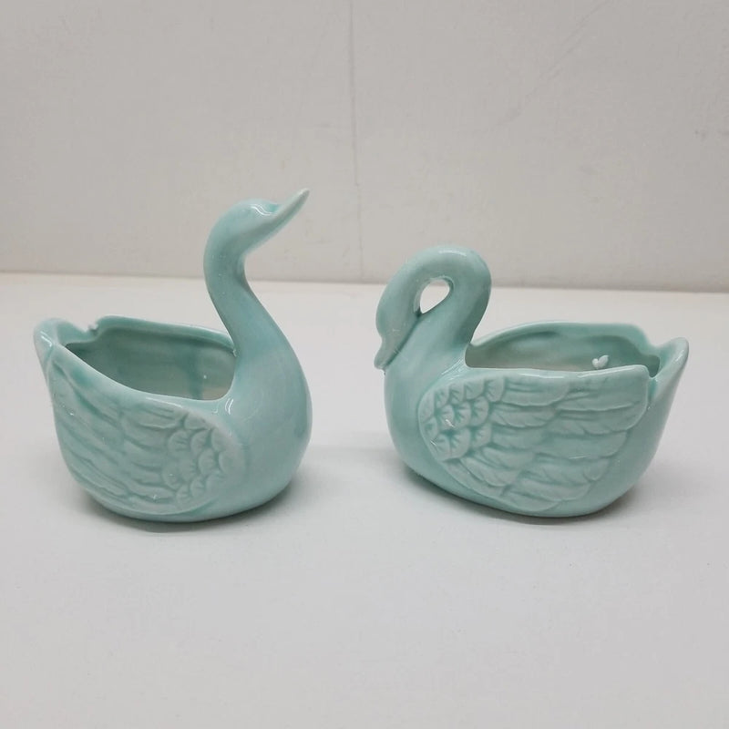 Pair of light blue ceramic swan planters with curved bodies and open top