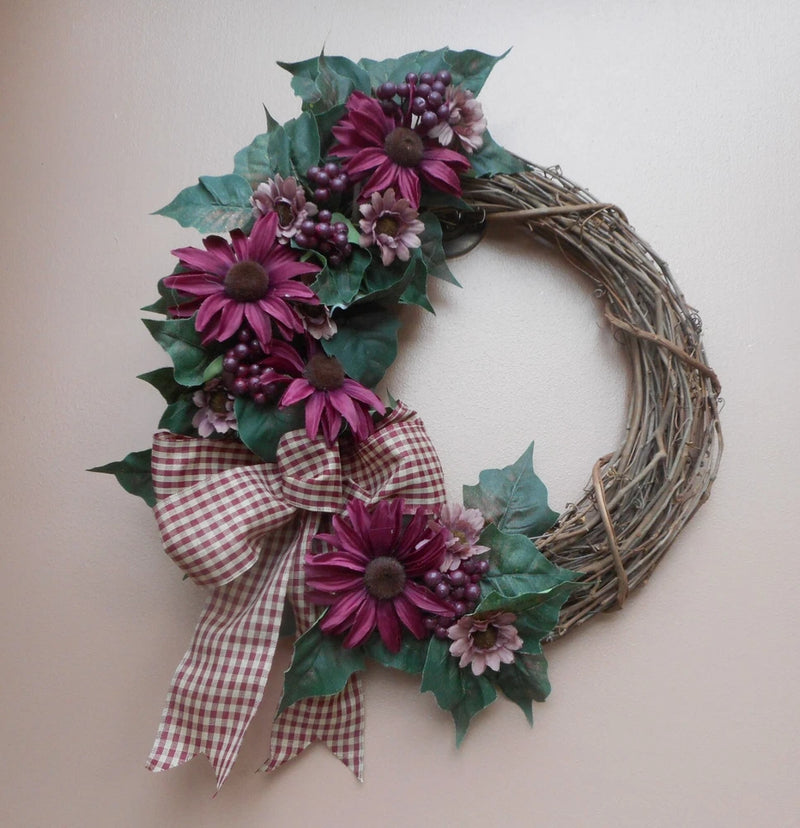 Grapevine wreath with burgundy purple flowers, berry sprigs, and plaid bow