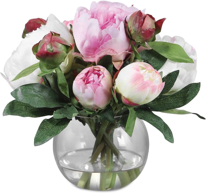 Peony bouquet in clear glass vase with pink and white peony blooms and green leaves