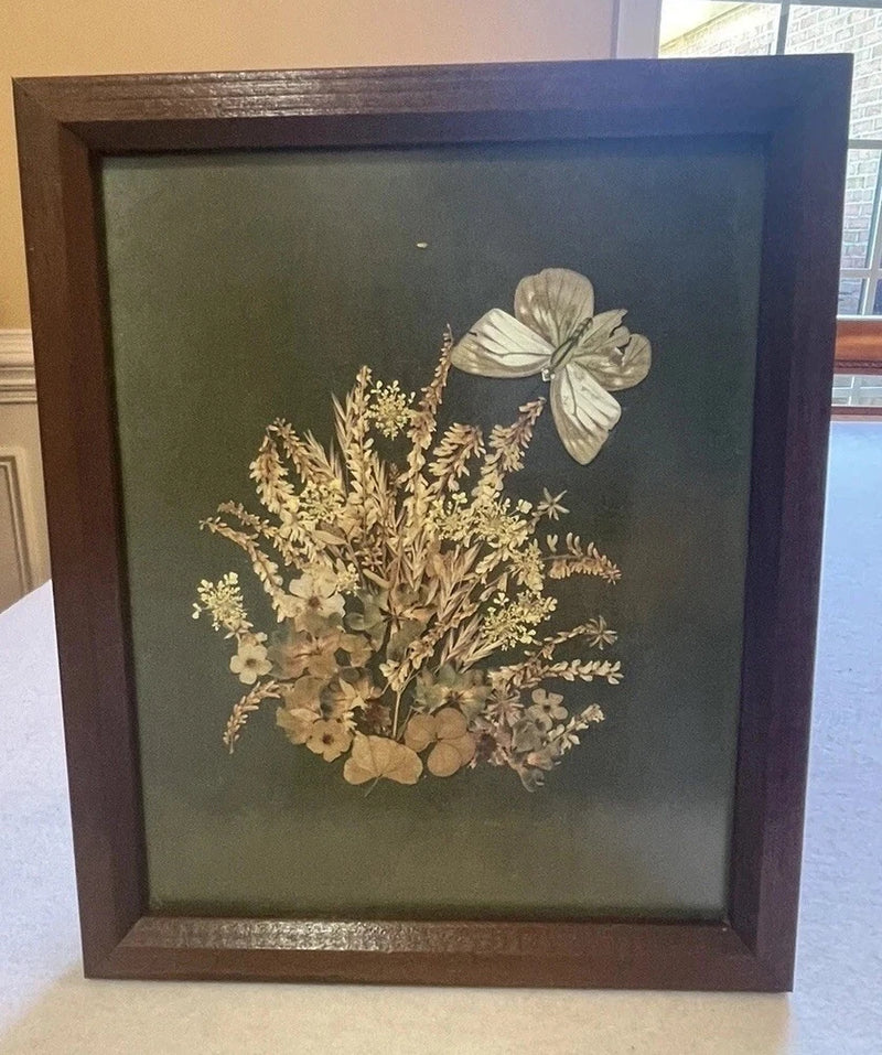 Framed pressed flower wall art with butterfly and dried botanical arrangement in dark mat