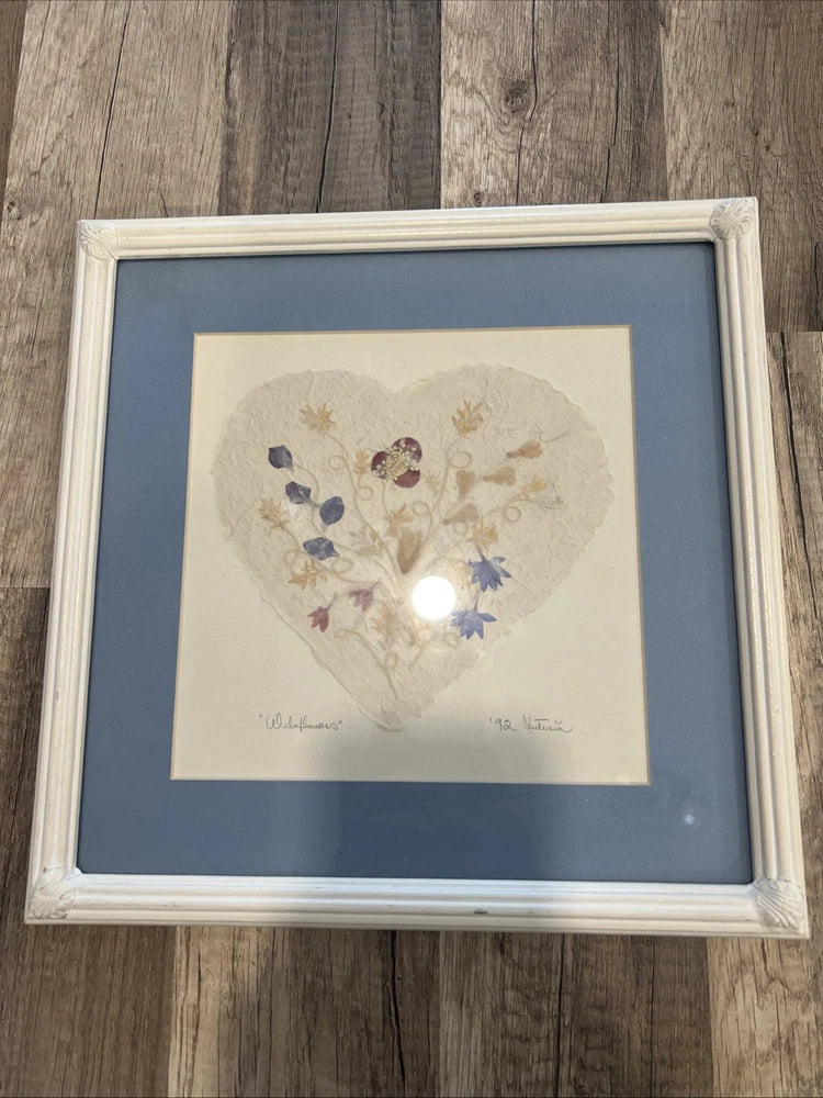 Framed pressed wildflower art with heart arrangement, pale dried flowers, blue mat