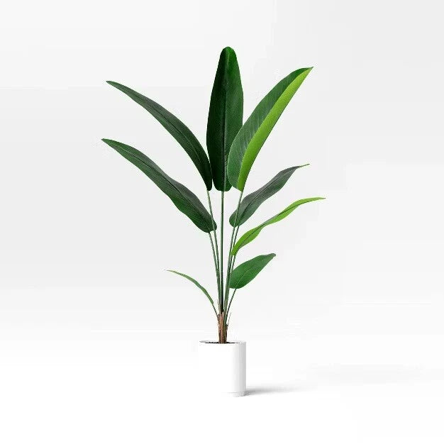 Artificial bird of paradise plant with tall faux green leaves in a white pot