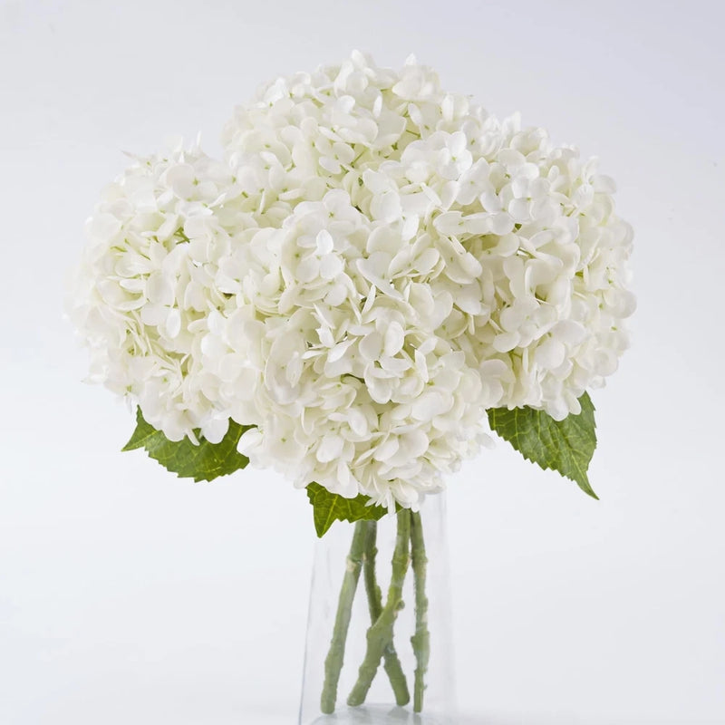 White artificial hydrangea bouquet with green leaves and multiple full flower heads