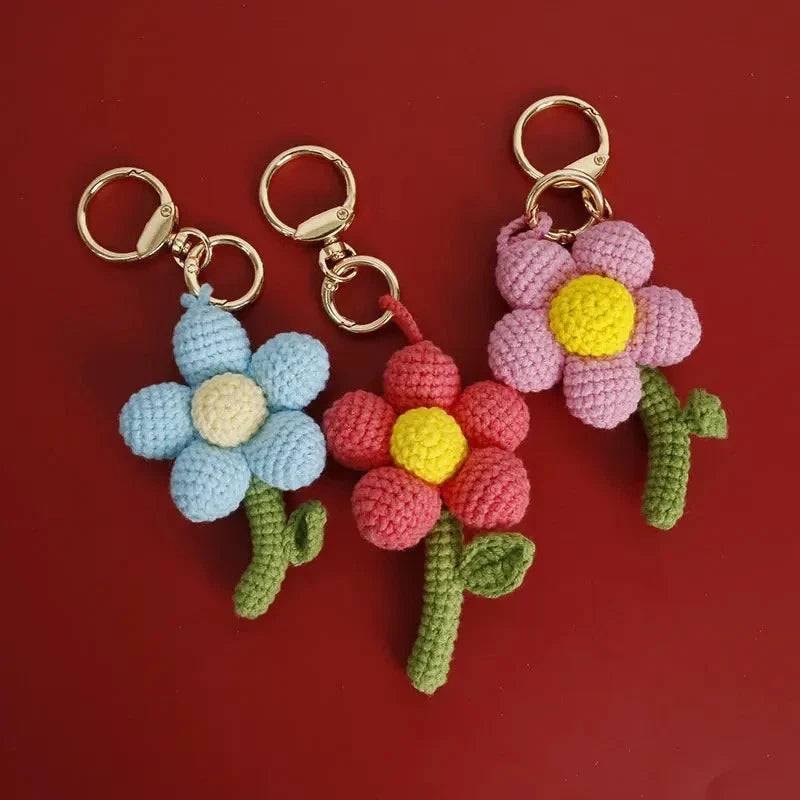 Crochet flower bouquet keychain with blue, pink, red blooms, yellow centers, and green leaves