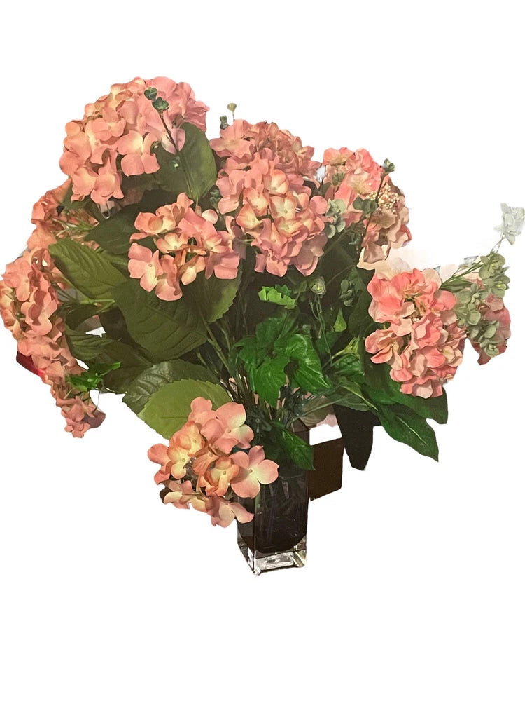 Artificial pink hydrangea silk flower bouquet with buds and green foliage, in clear vase