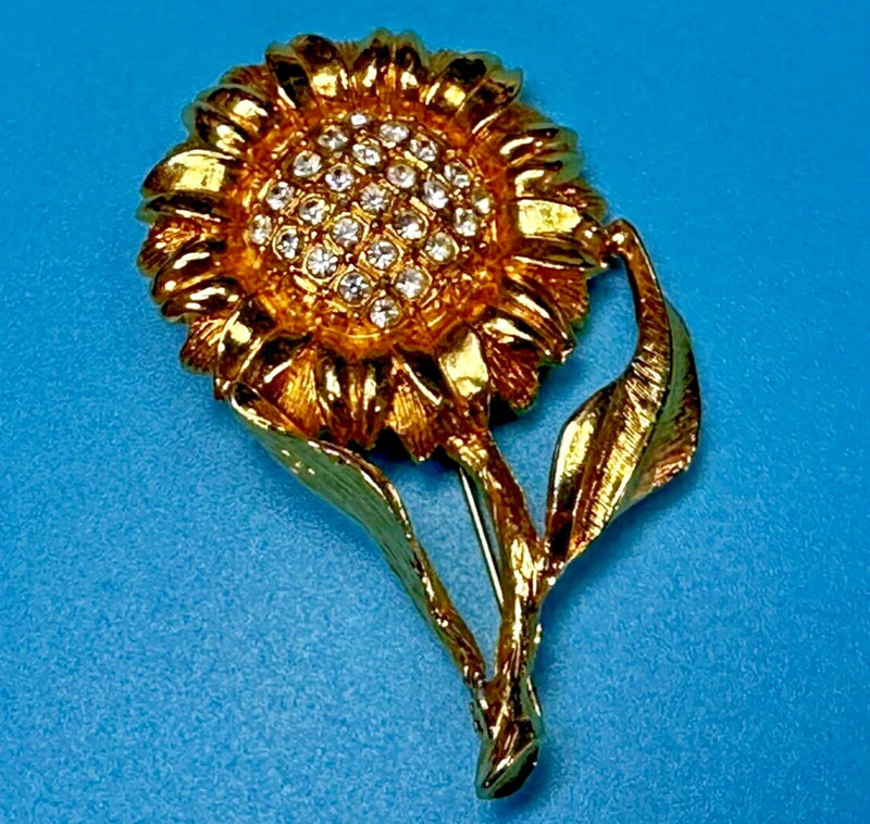 Gold-tone sunflower brooch pin with clear rhinestone accents and leaf details