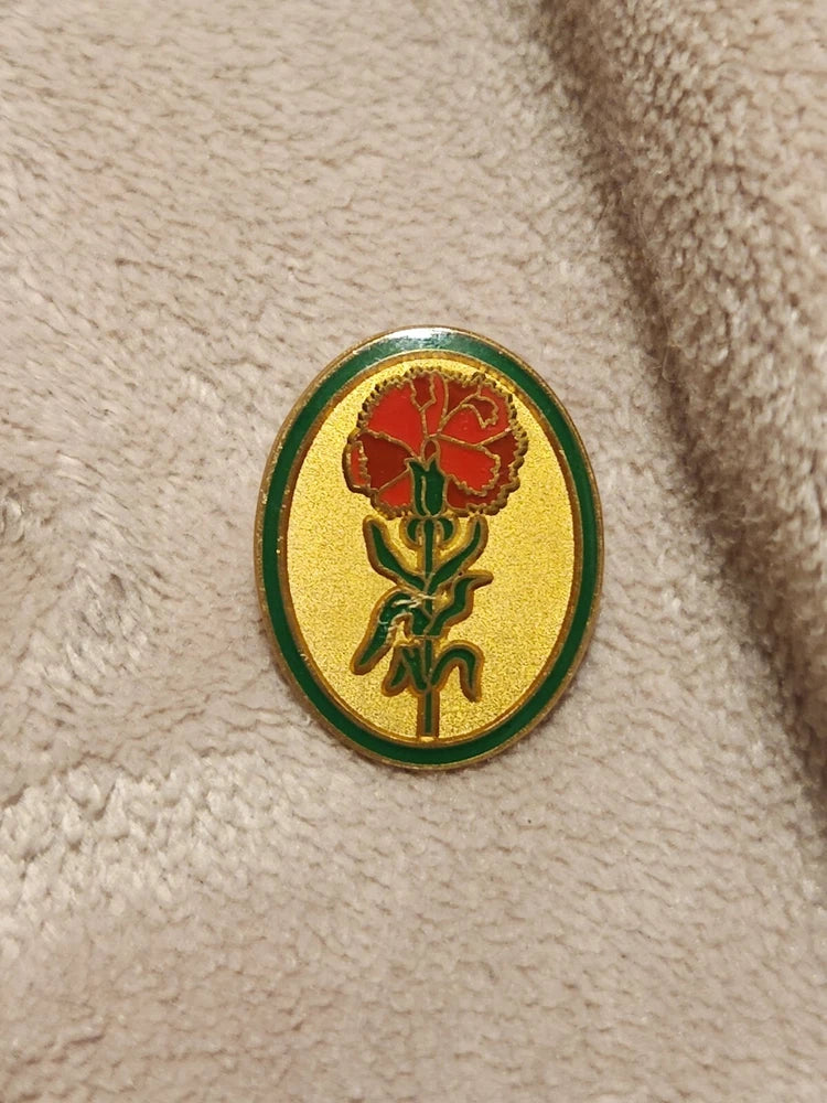 Oval enamel lapel pin with red carnation flower detail