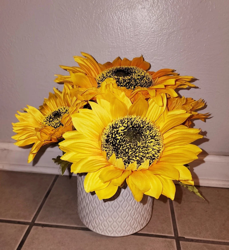 Yellow faux sunflower arrangement with dark centers in a white textured ceramic pot