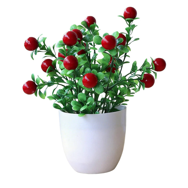 Small faux potted plant with green leaves and red round berries in a white pot