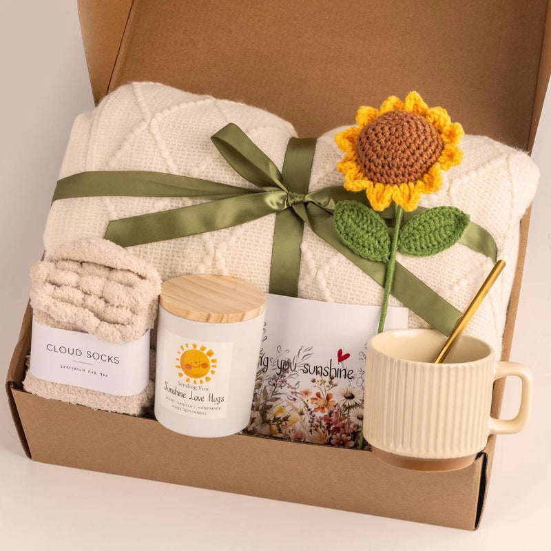 Care package gift basket with white towels, green ribbon, sunflower decor, mug, and candles