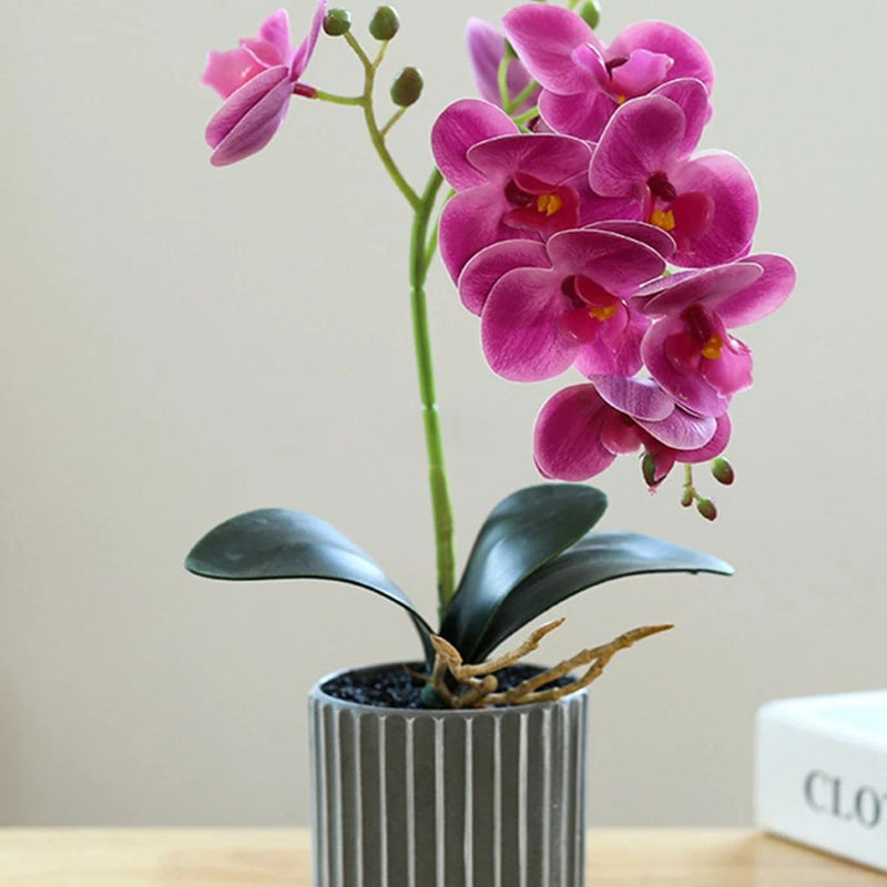 Artificial orchid bonsai in striped gray pot, pink blossoms and dark green leaves