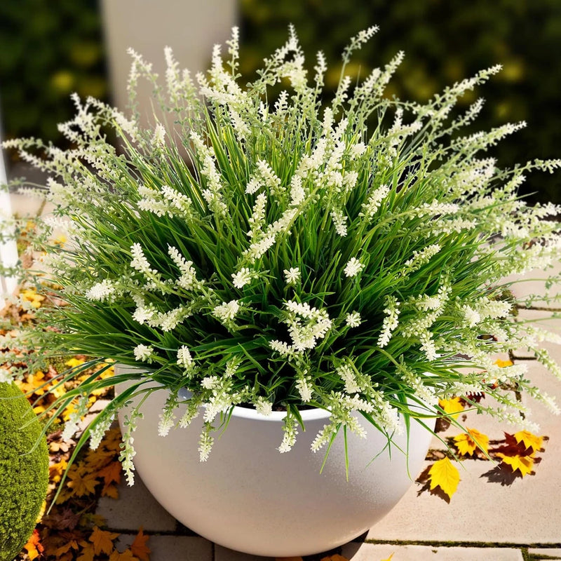 Artificial faux monkey grass plant with white tufted blooms in round outdoor pot