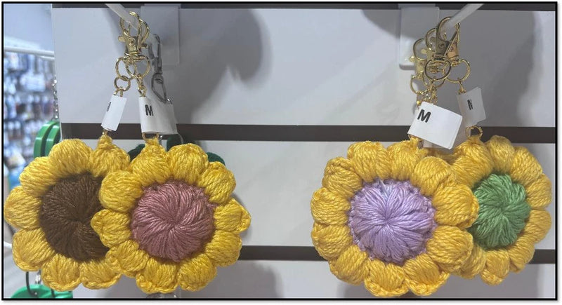 Crochet sunflower keychain with yellow petals, purple center, green detail, gold clasp