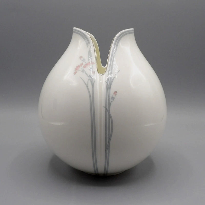 White ceramic tulip vase with red flowers and blue-gray stems