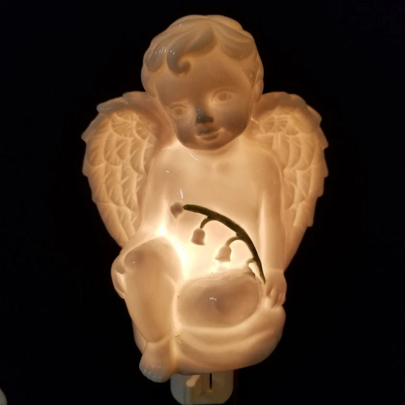 Angel night light figurine holding a lily of the valley flower, warm glowing base