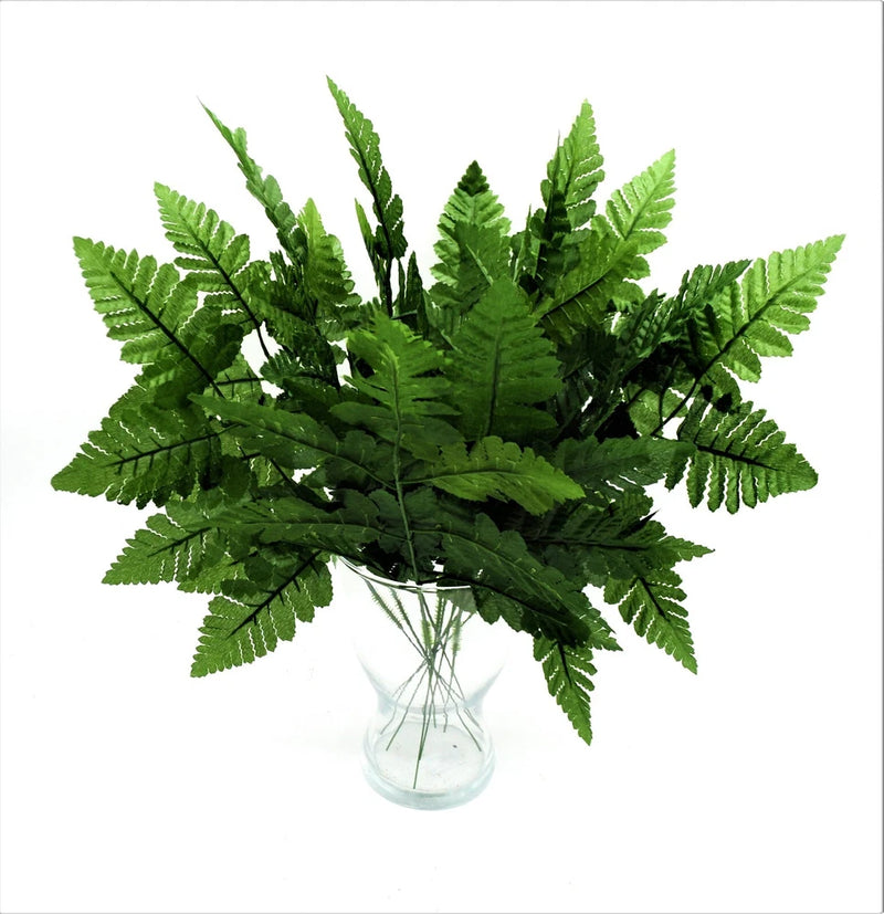 Artificial green fern leaf spray in a clear glass vase for home decor
